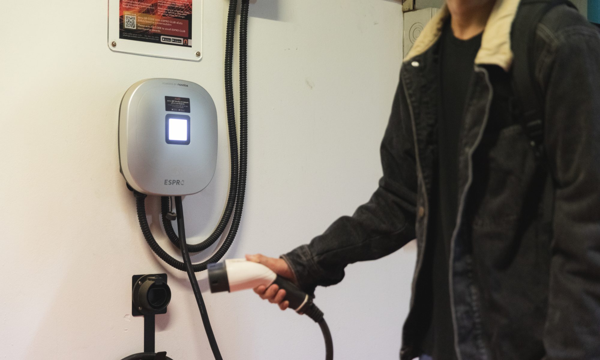 A man charging an electric car at a charger.